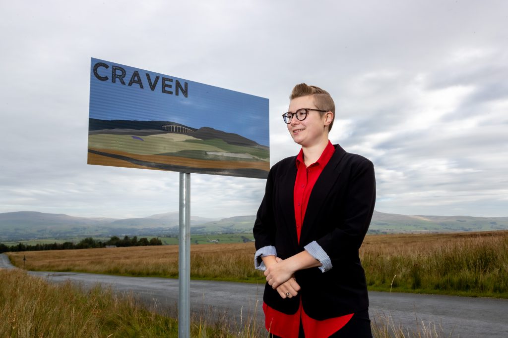Artist standing by her road side sign