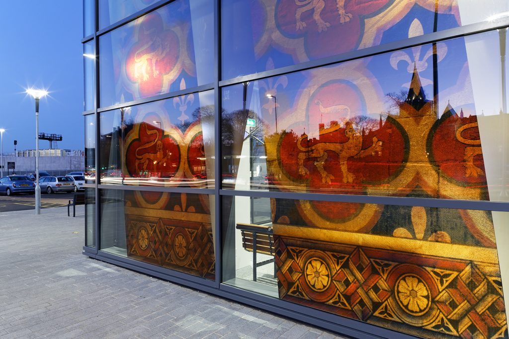 Close up of vinyl artwork on glass building illuminated from inside the glass building