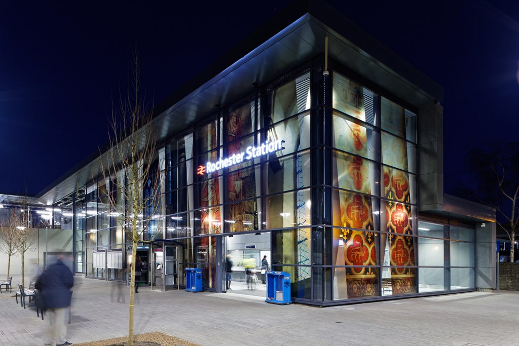 Rochester Station at night with vinyl artwork illuminated from inside the glass building